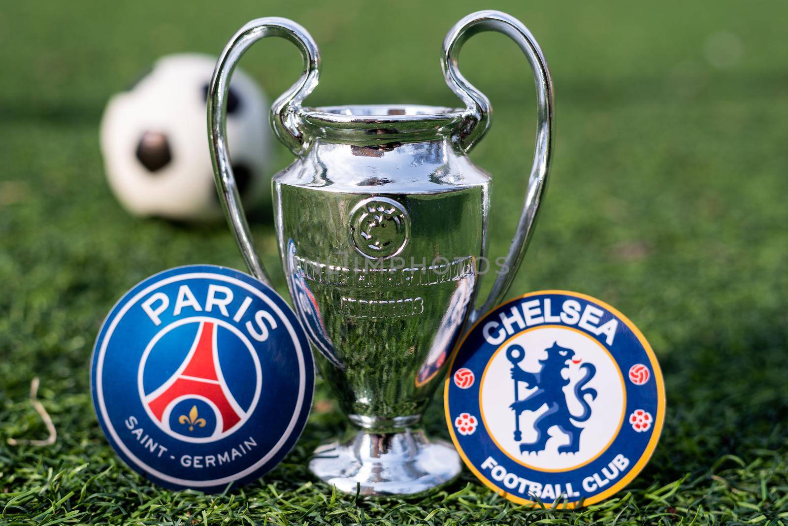 April 16, 2021 Moscow, Russia. The UEFA Champions League Cup and the emblems of the football clubs Paris Saint-Germain F. C. and Chelsea F. C. London on the green grass of the lawn.