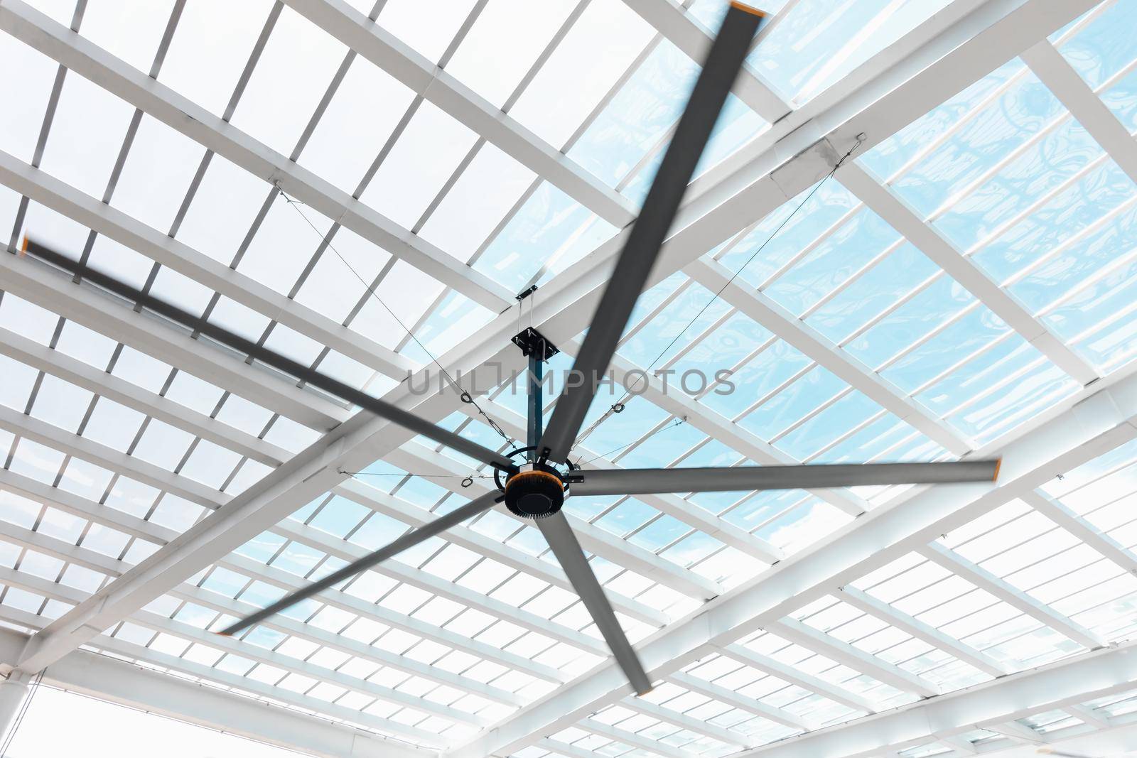 Ventilation Electrical Ceiling Fan Indoor Hall of Building, Luxury Modern Architecture Roofing Transparent Grass and Structure Metal Frame. Electric Ventilator Fan Against Geometric Structures Frame