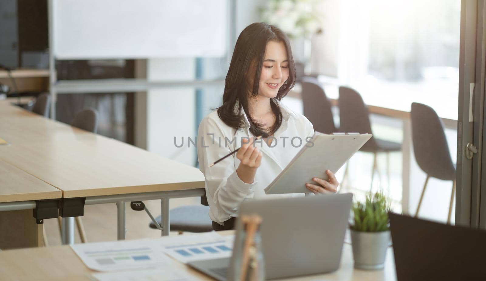 Portrait of successful young Asian businesswoman working with financial report at her office.