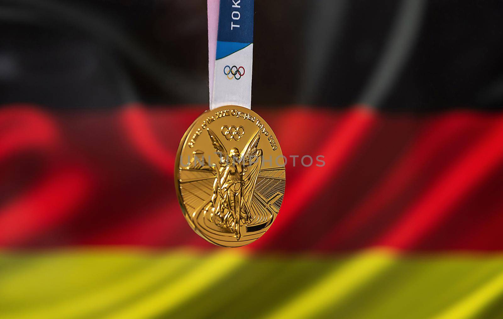 April 25, 2021 Tokyo, Japan. Gold medal of the XXXII Summer Olympic Games 2020 in Tokyo on the background of the flag of Germany.