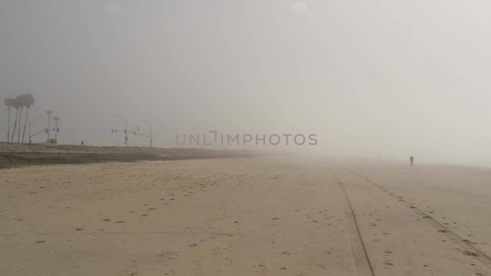 Sandy misty beach, Encinitas California USA. Pacific ocean coast, dense fog brume, empty sea shore. Coastline near Los Angeles, milky smog haze. Gloomy weather on shoreline. Cloudy grey monochrome sky