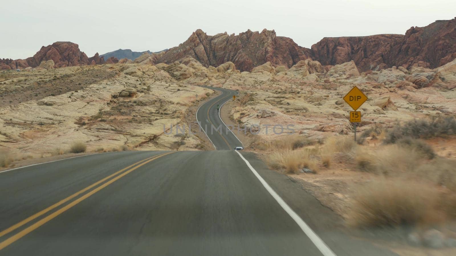 Road trip, driving auto in Valley of Fire, Las Vegas, Nevada, USA. Hitchhiking traveling in America, highway journey. Red alien rock formation, Mojave desert wilderness looks like Mars. View from car.