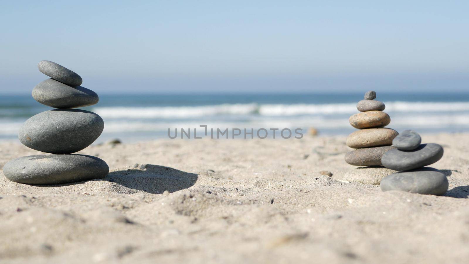 Rock balancing on ocean beach, stones stacking by sea water waves. Pyramid of pebbles on sandy shore by DogoraSun
