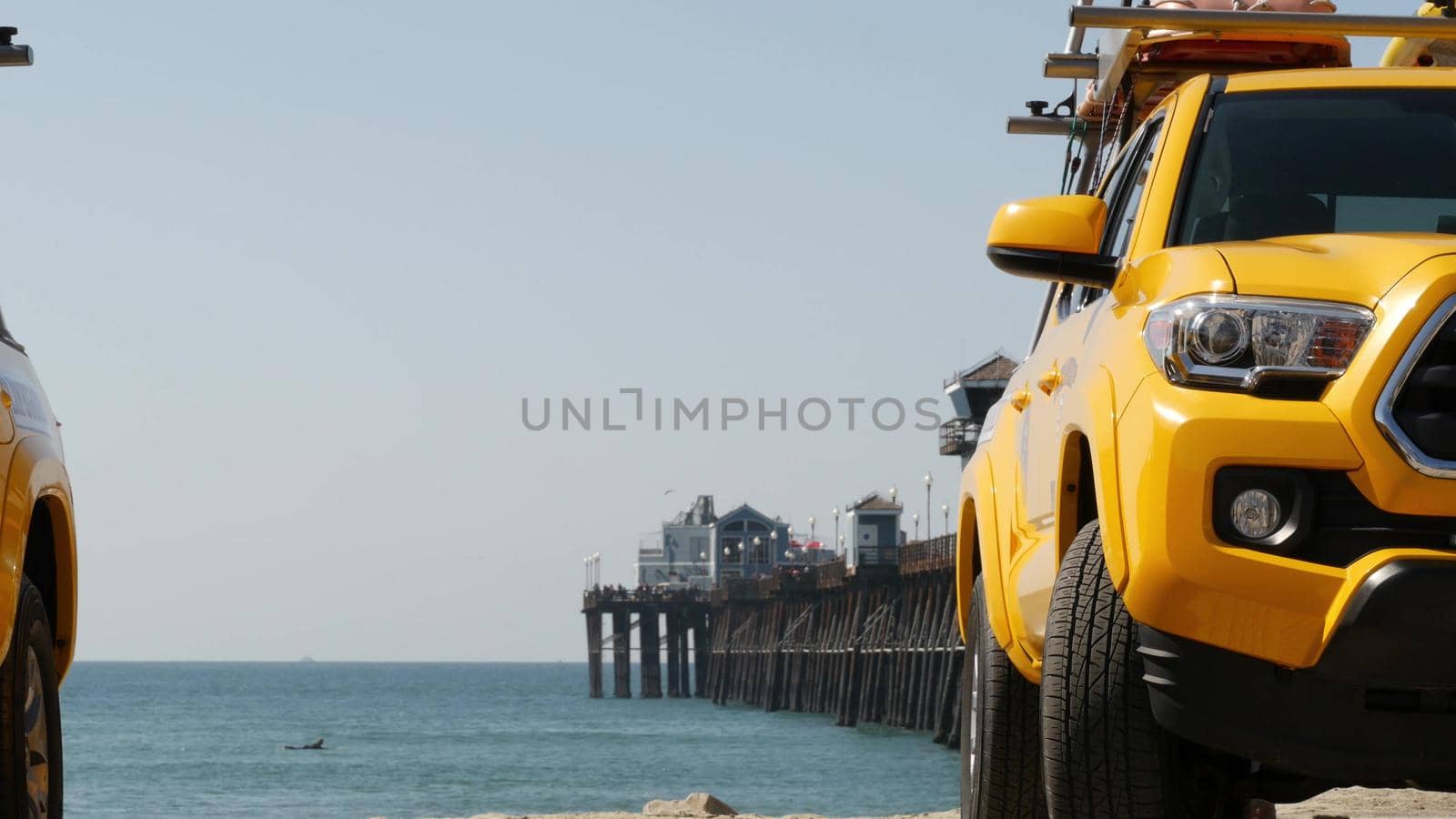 Yellow lifeguard car, Oceanside beach, California USA. Coastline rescue life guard pick up truck, lifesavers vehicle. Iconic auto and ocean coast. Los Angeles vibes, summertime aesthetic atmosphere.