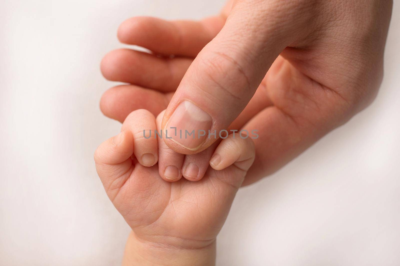 A newborn holds on to mom's, dad's finger. Hands of parents and baby close up. A child trusts and holds her tight by Vad-Len