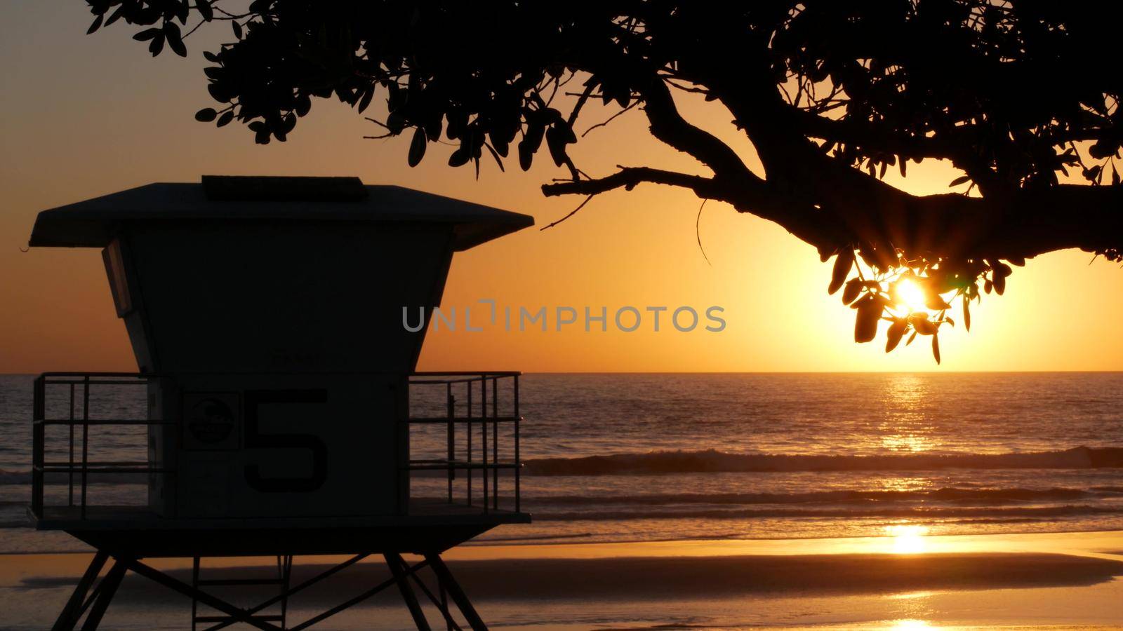 Lifeguard watch tower, sunny sunset beach, Oceanside USA. Rescue station, waterfront watchtower hut and tree leaves, pacific ocean coast atmosphere. California summertime aesthetic, Los Angeles vibes.