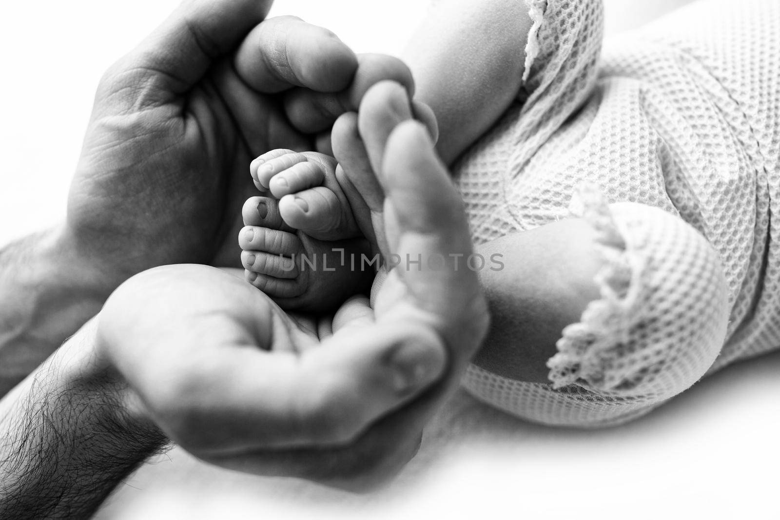 Feet of a newborn in the hands of a father, parent. Black and white.  by Vad-Len