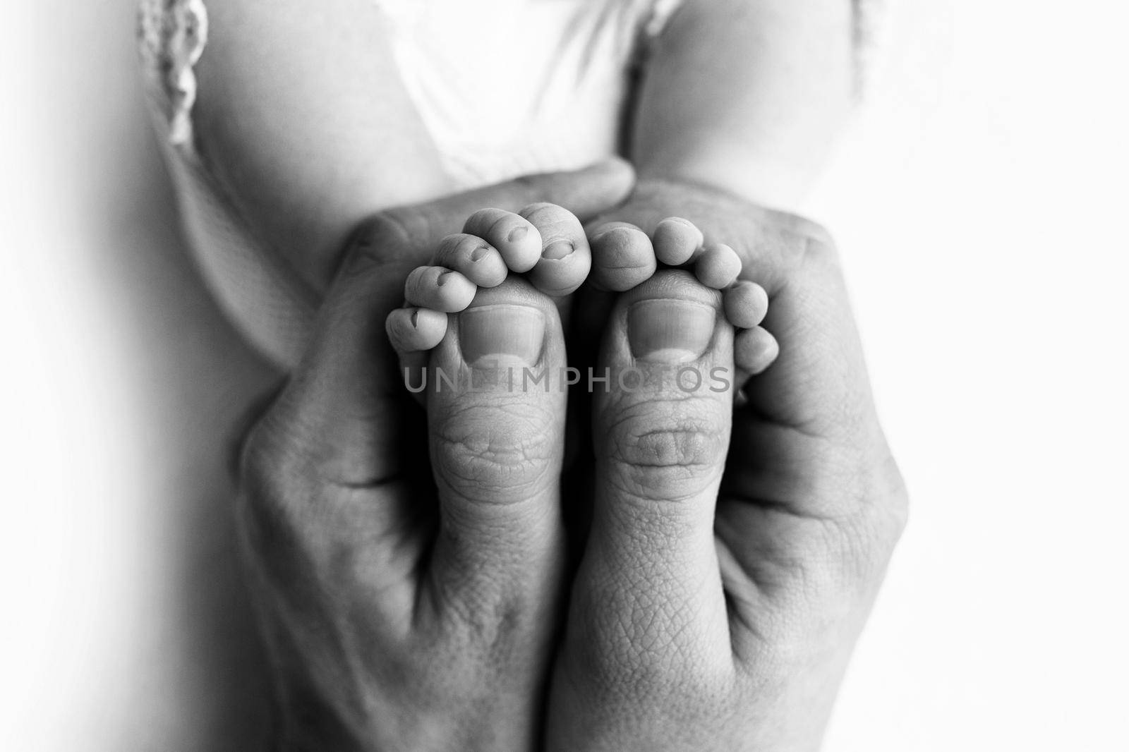 Feet of a newborn in the hands of a father, parent. Studio photography, black and white. Happy family concept. High quality photo