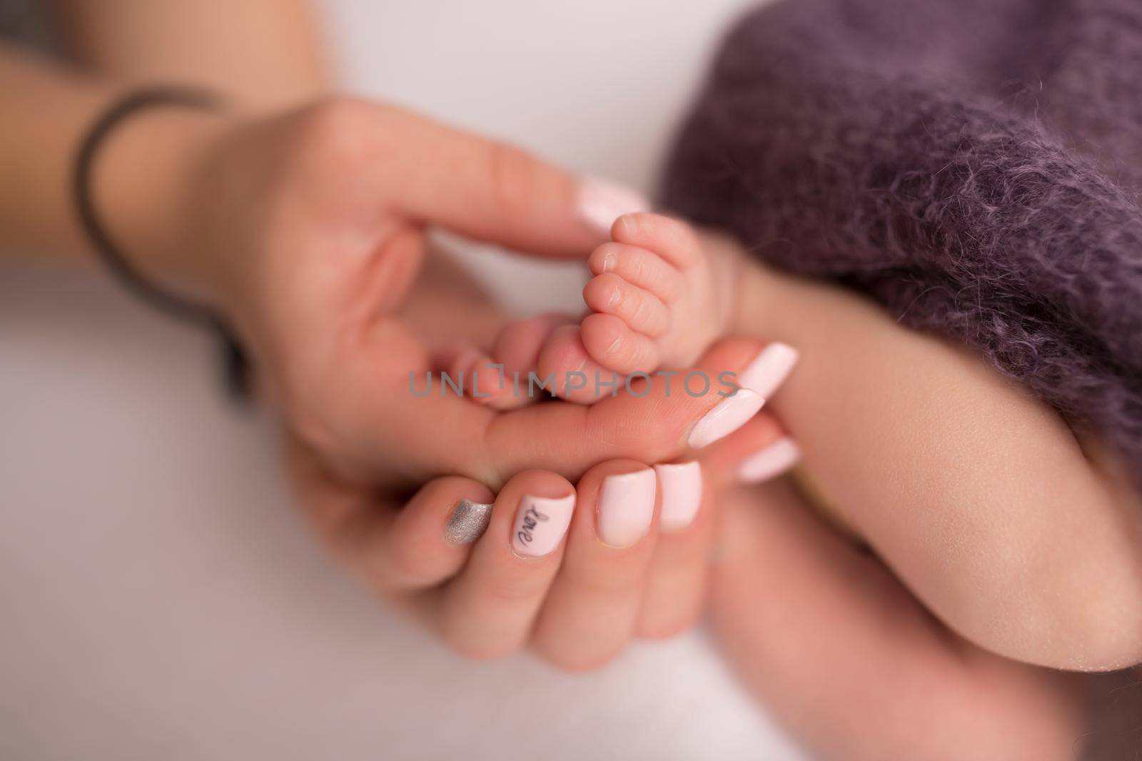 Children's feet in hold hands of mother and father. Mother, father and Child. Happy Family people concept. by Vad-Len