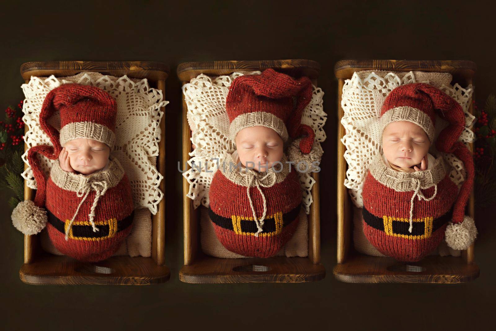 Three newborn brothers sleep in cribs dressed as elves. High quality photo
