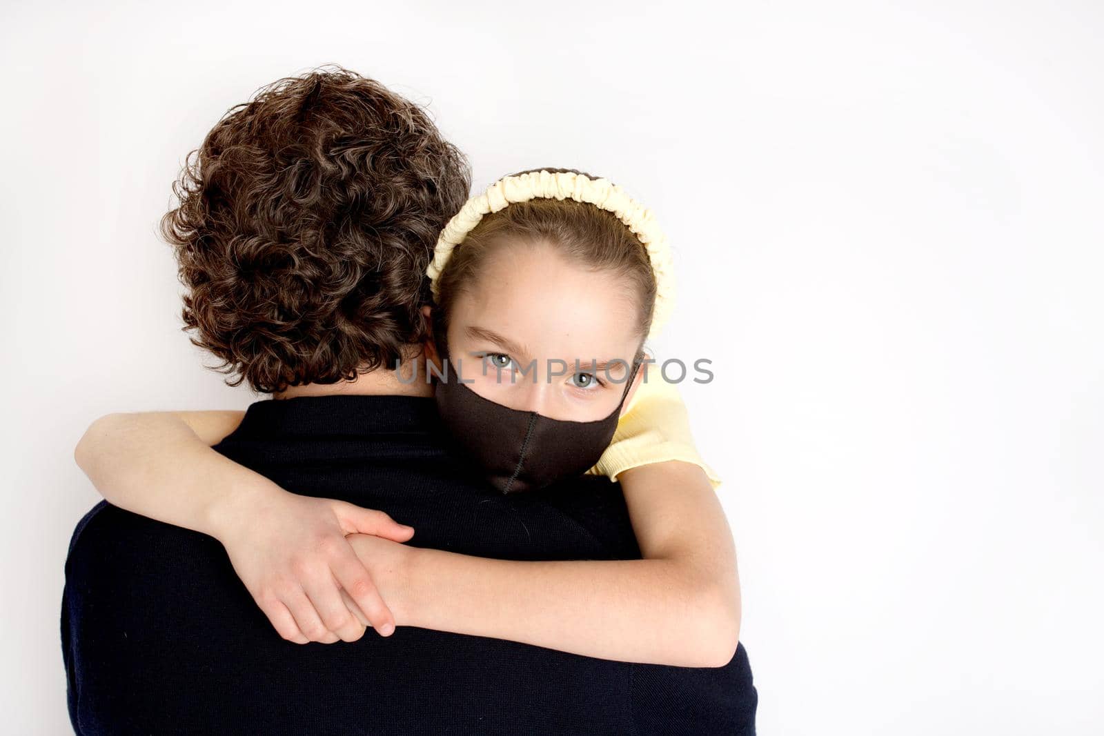 A teenage girl in a black antibacterial mask and a yellow T-shirt in her father's arms. by Vad-Len