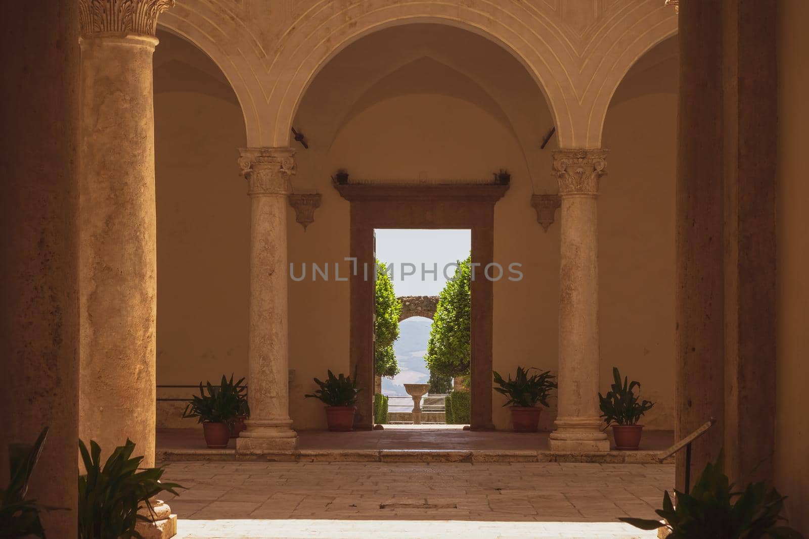 View of the beautiful Cloister of Piccolomini Palace in the famous town of Pienza, Tuscany, Italy. In the distance the view of the Tuscan countryside in the summer season.