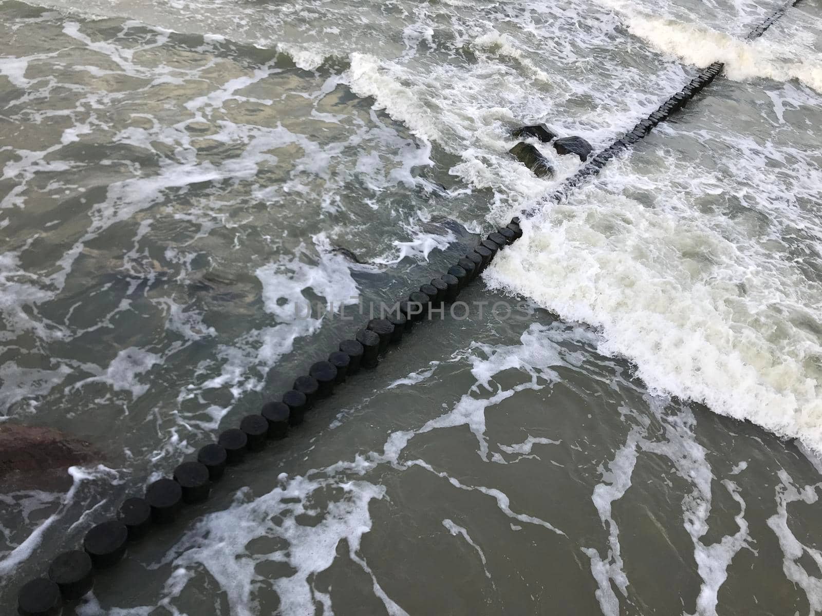 Breaking waves on a wooden breakwater on the Baltic Sea coast. High quality photo