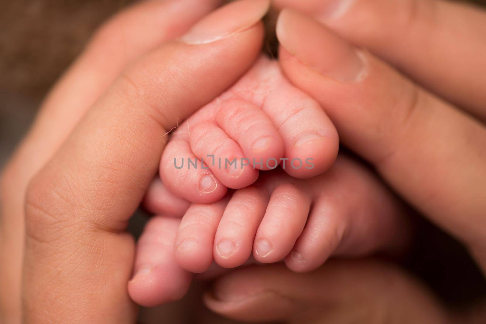 Children's feet in hold hands of mother and father. Mother, father and Child. Happy Family people concept. by Vad-Len