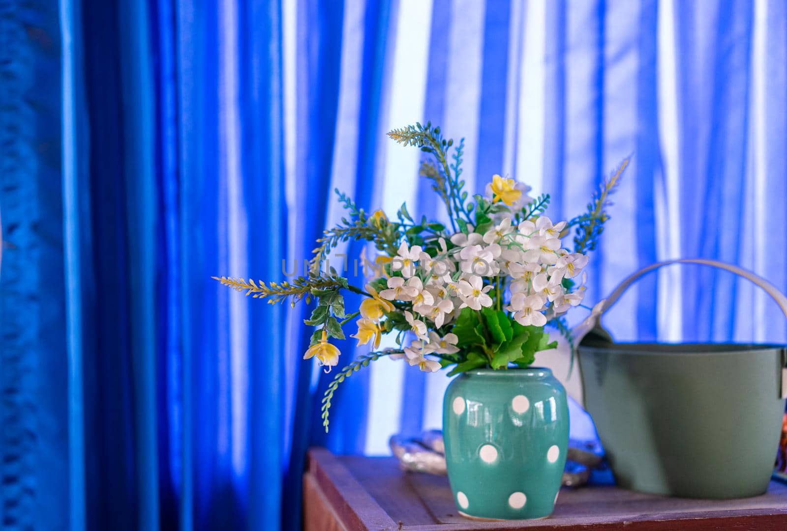 Fake flowers in a vase on wood table