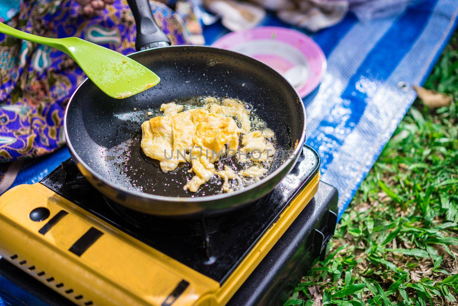 cooking omelet on picnic gas stove for breakfast between camping