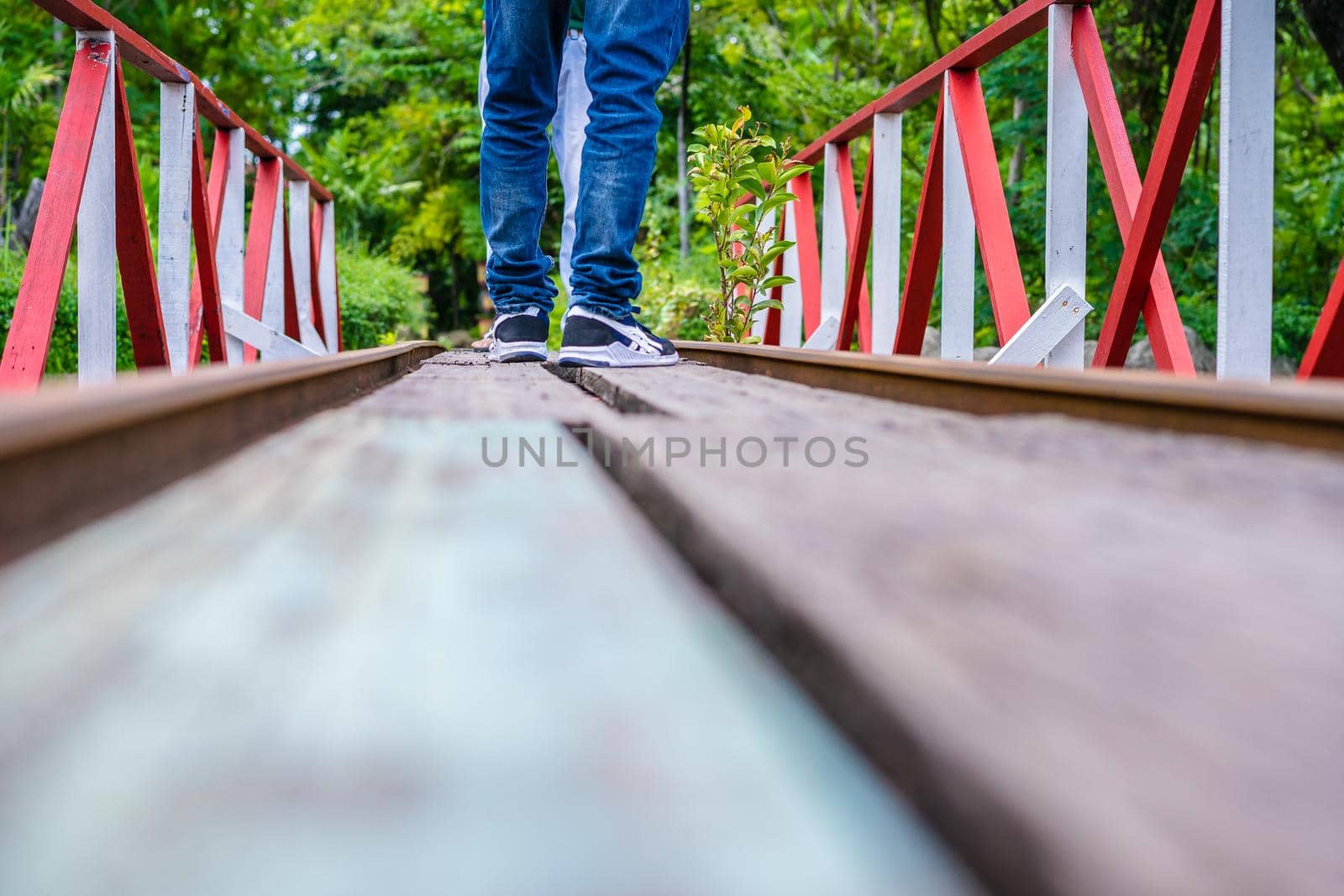 Man standing on railroad tracks through the park