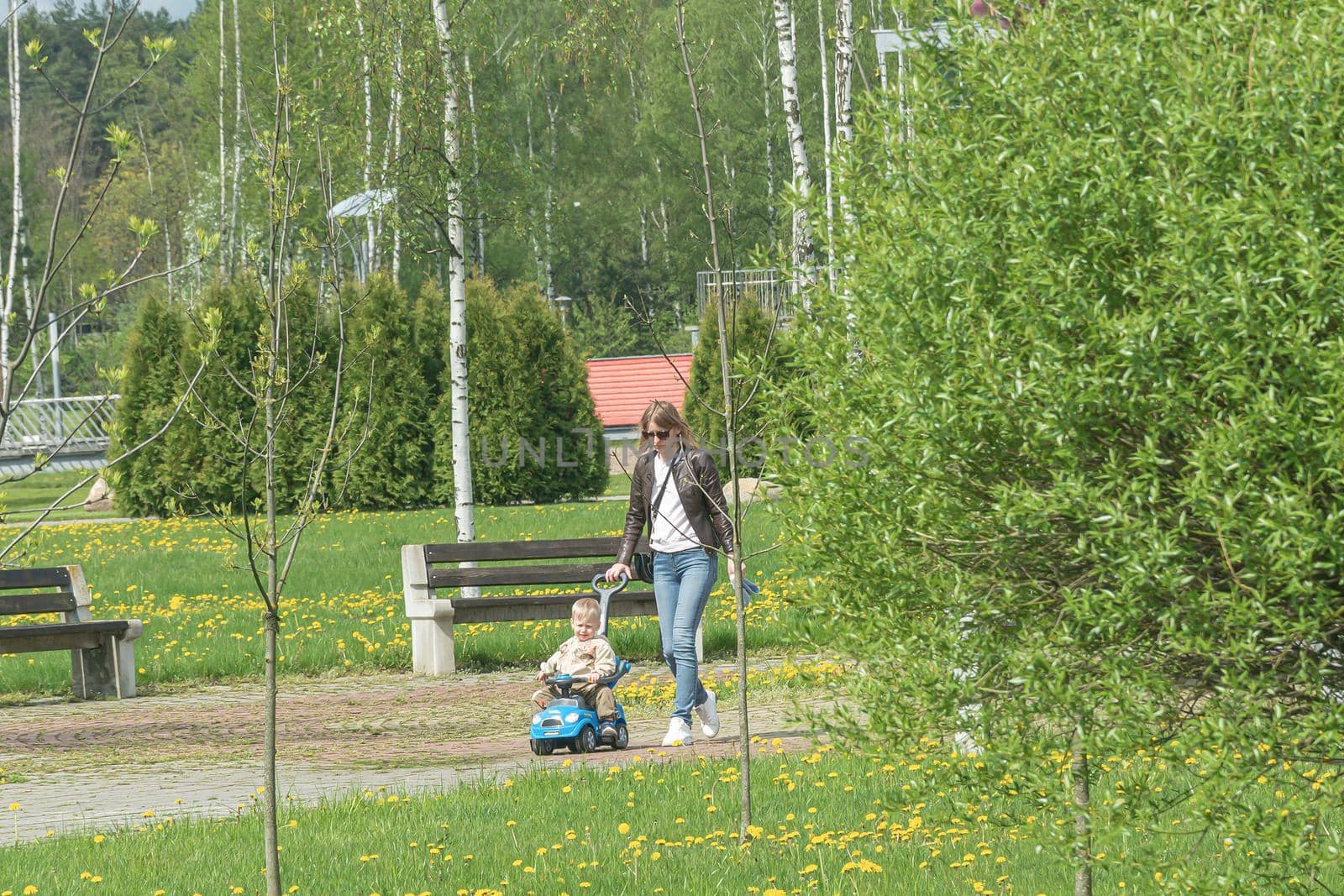 Russia, Saratov - May 15, 2021: Mom and child walk along the alley of the park. Stock photography.