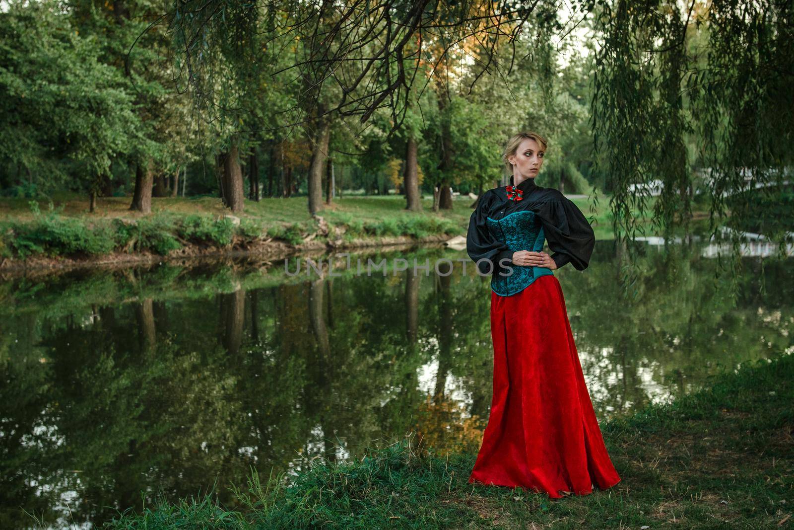 Girl model with white hair in a retro dress with ruffles in a green park