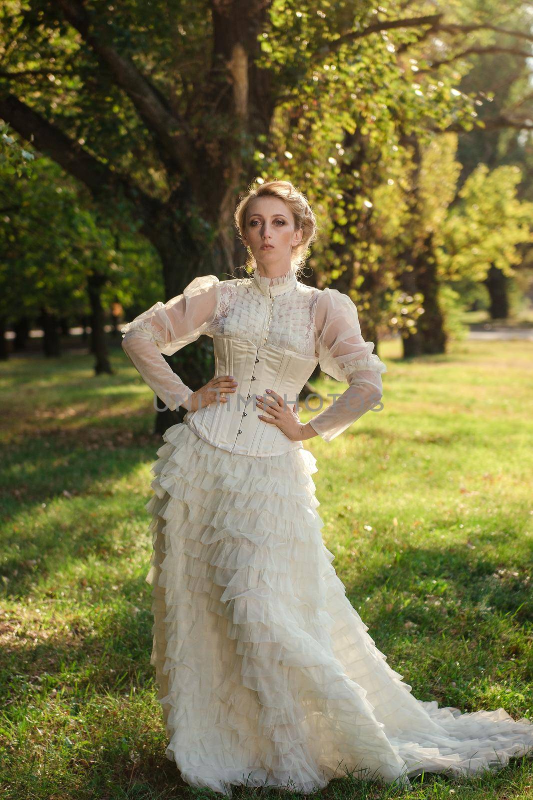 Girl model with white hair in a retro dress with ruffles in a green park