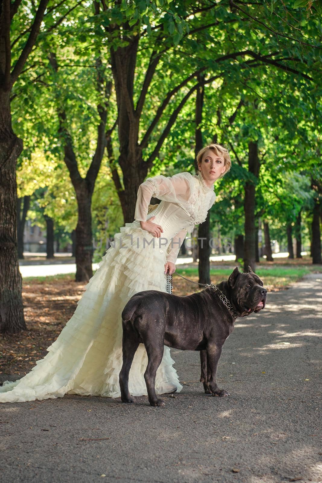 Girl in an old dress with ruffles and a big dark dog