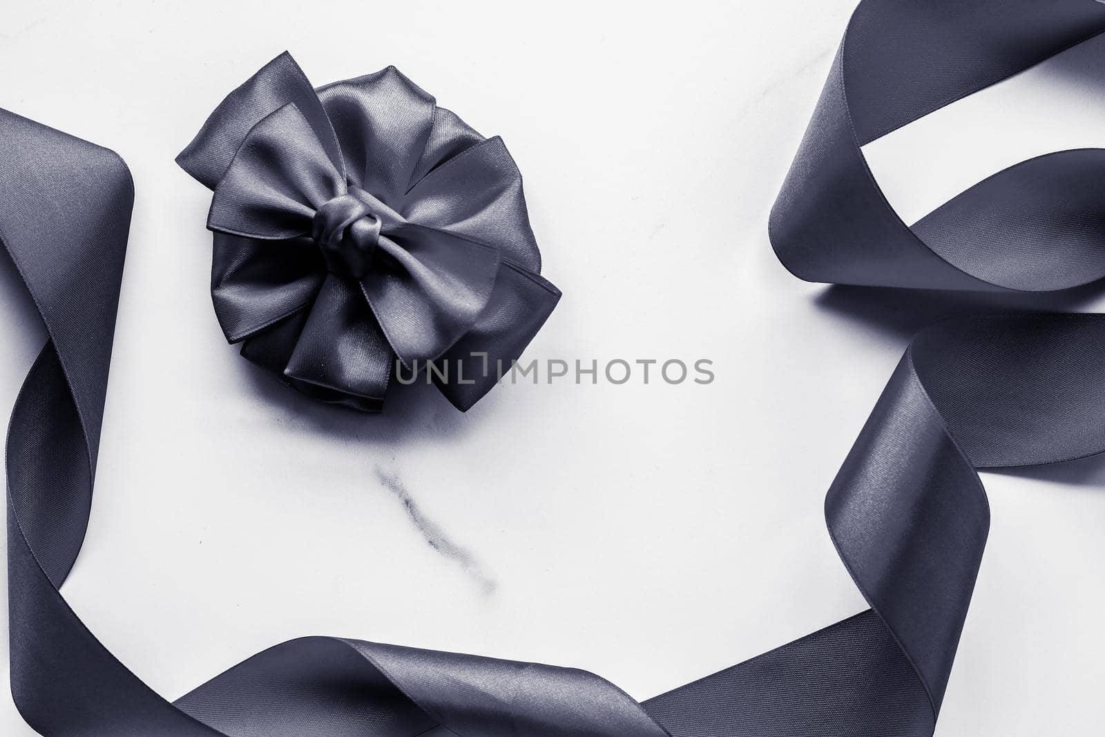 Holiday gift, decoration and sale promotion concept - Black silk ribbon and bow on marble background, flatlay