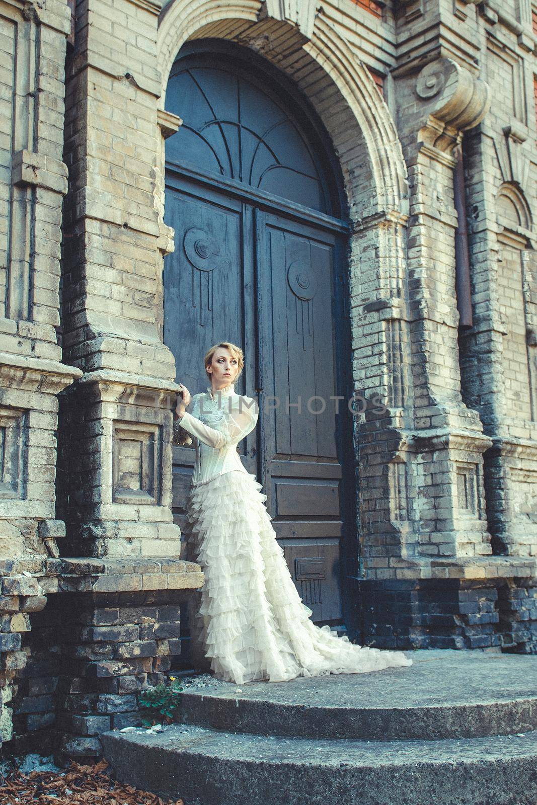 Blonde girl in a retro dress on the background of the old dark door of the building