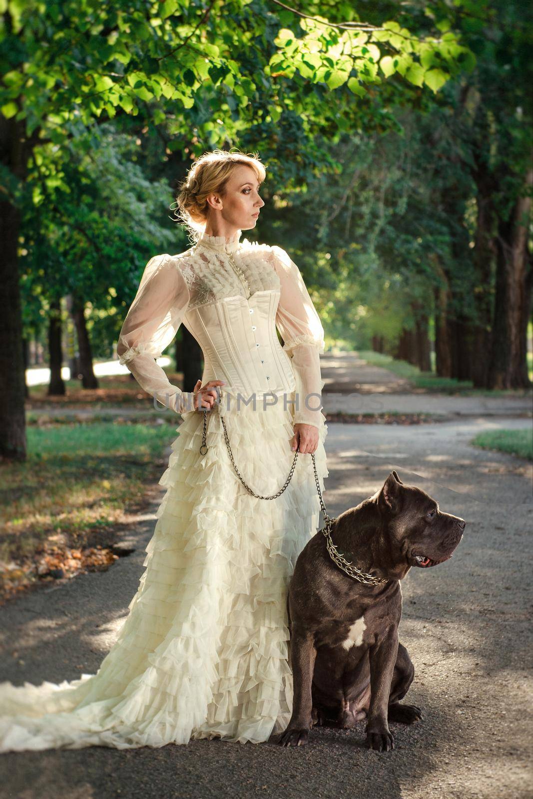 Girl in an old dress with ruffles and a big dark dog