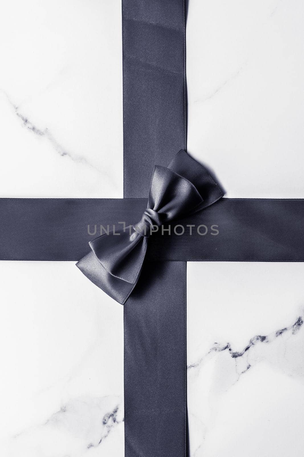 Black silk ribbon and bow on marble background, flatlay by Anneleven