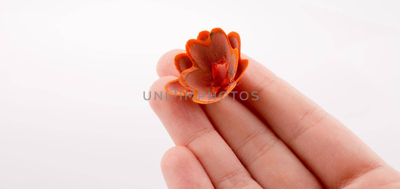 Color pencils shavings at the top of fingers on white background