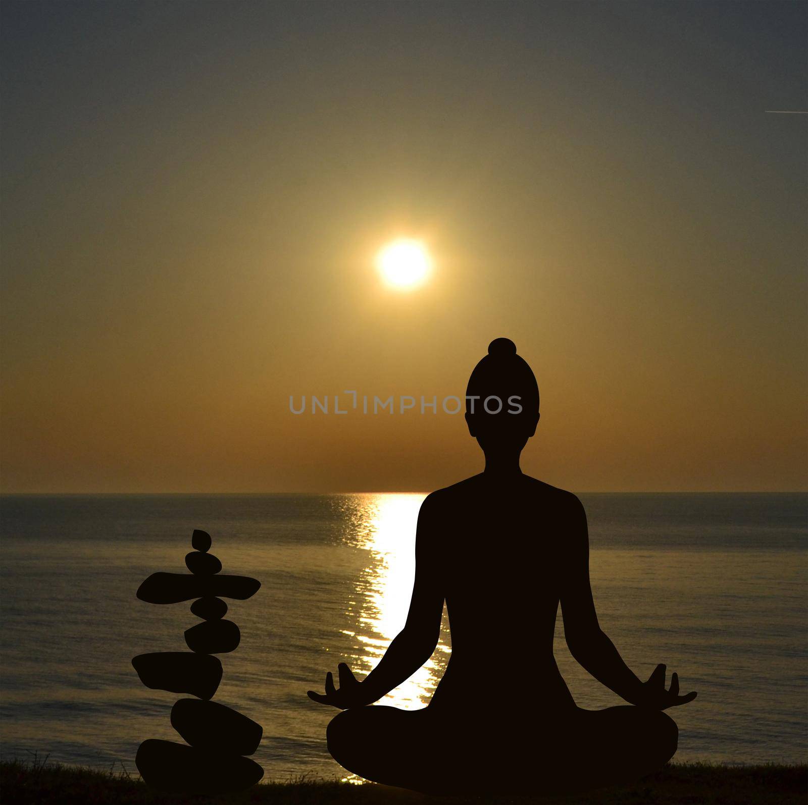 Silhouette of yogi in lotus position and a pile of stone at sea shore at sunrise