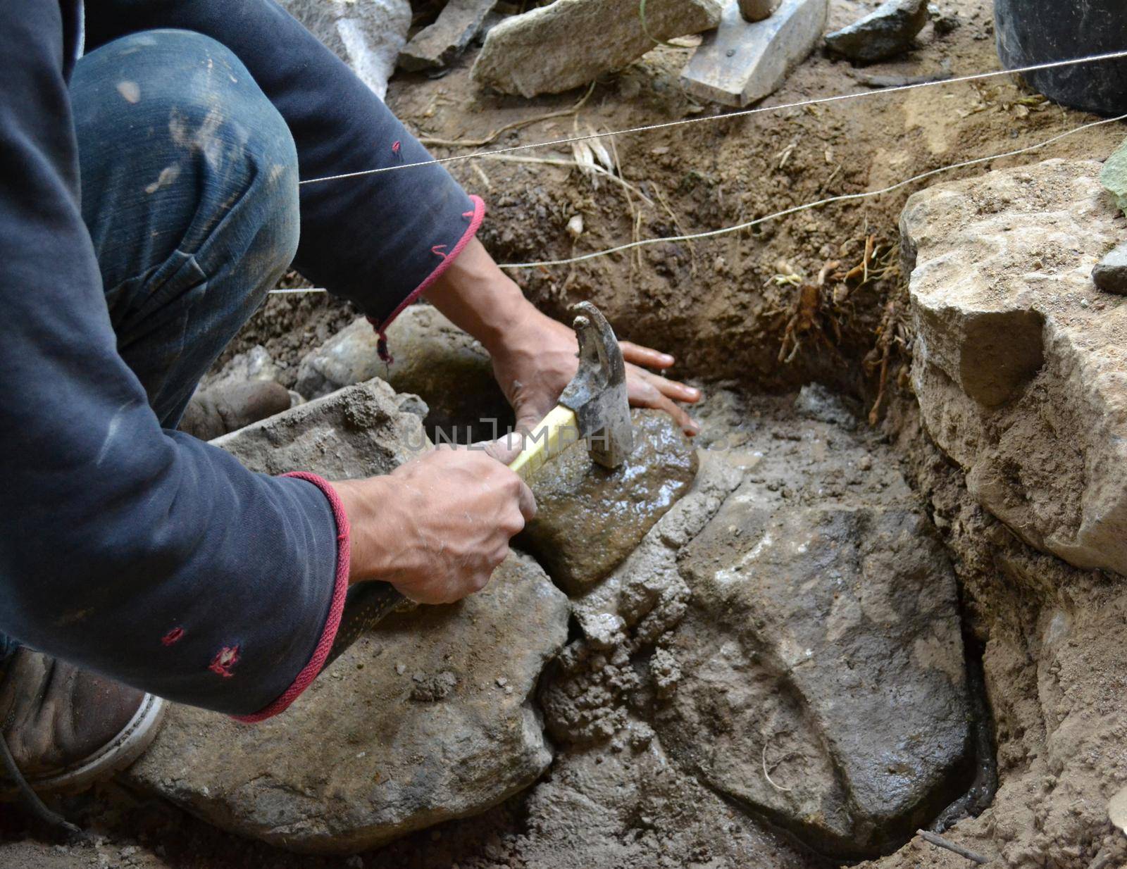 Construction worker working with hammer and natural stone