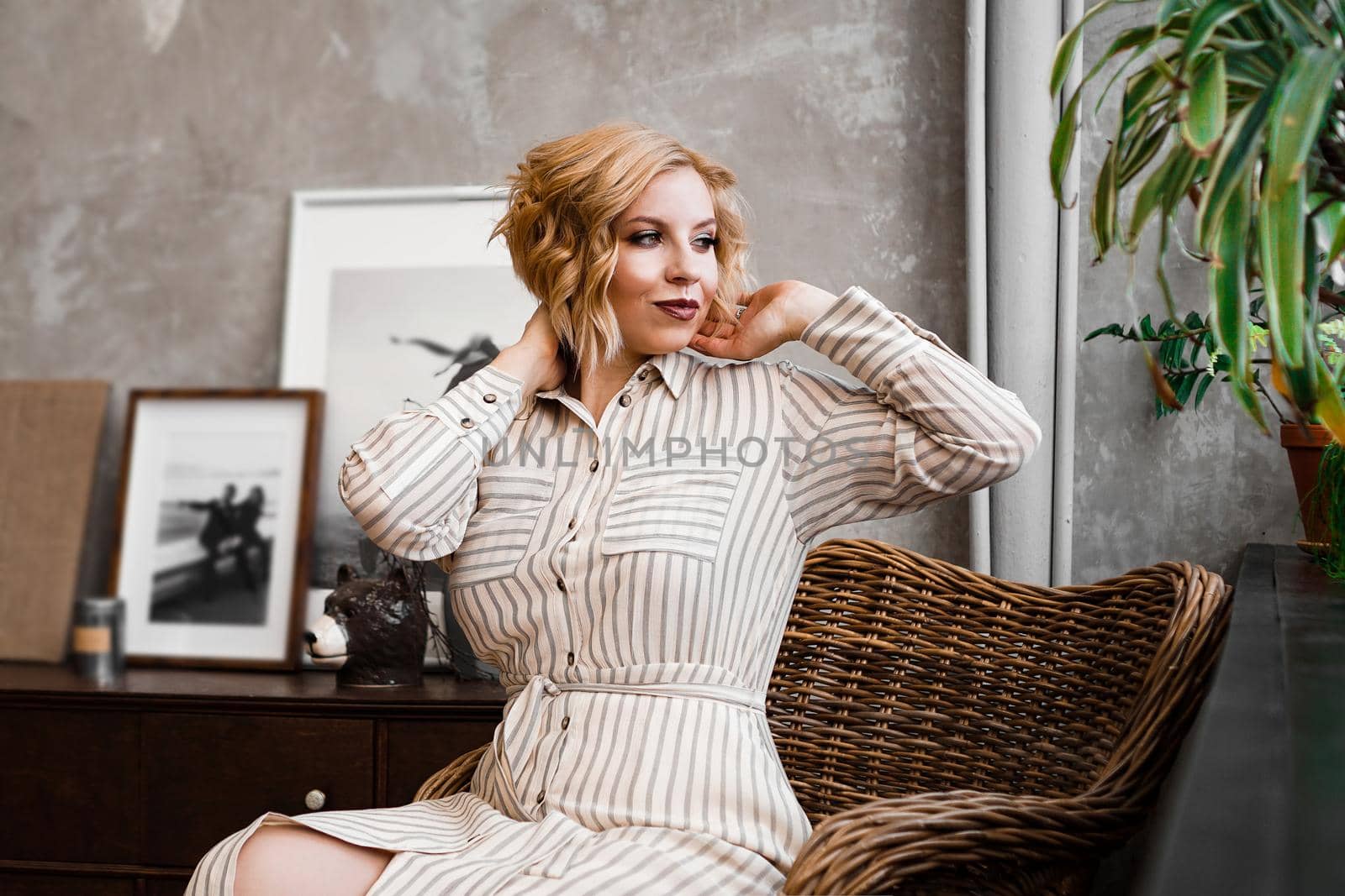 Beautiful young woman resting at home in a wicker chair near the window with plants