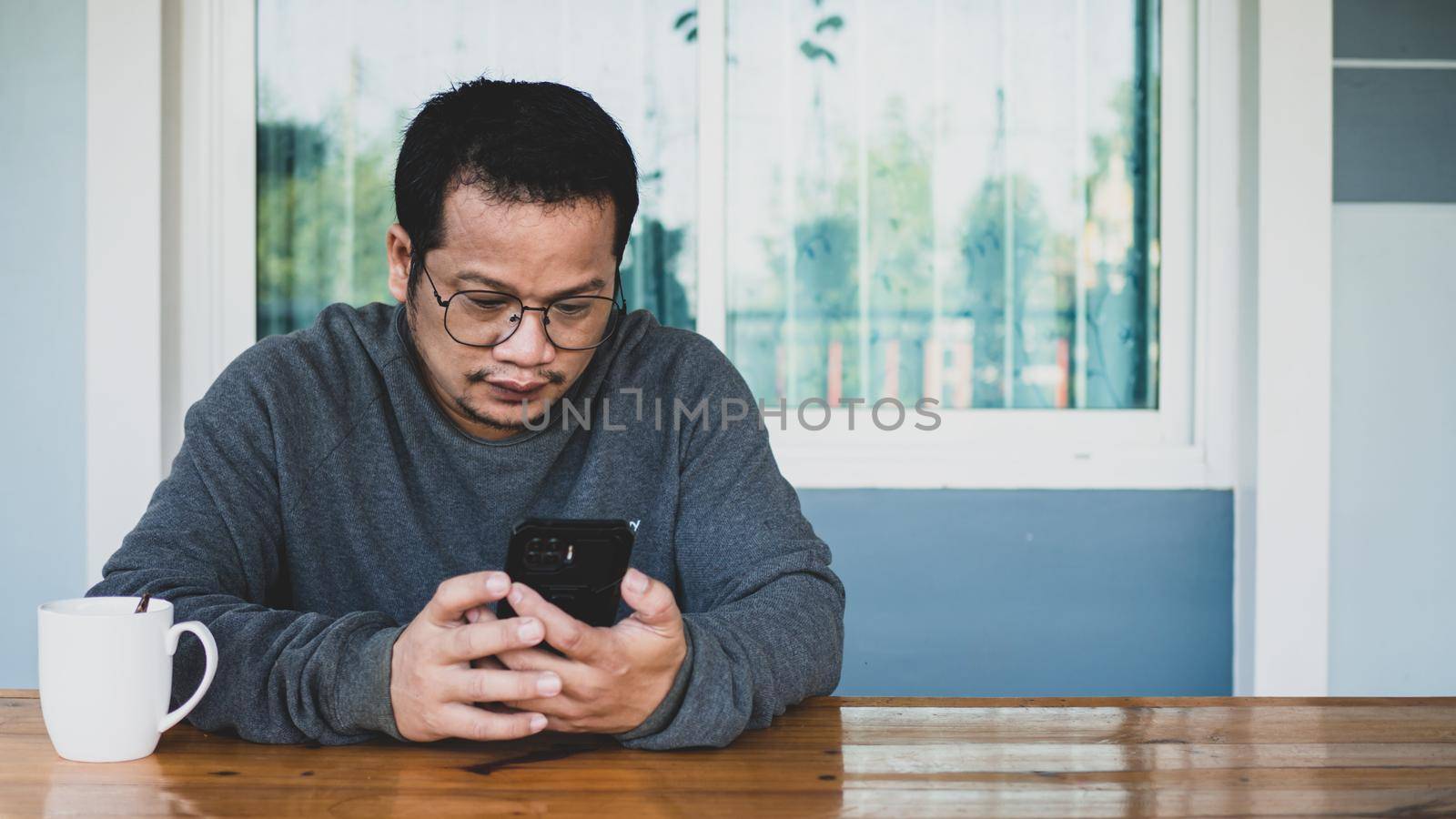 Asian men wearing long sleeves and eyeglasses. he is chatting in social media messenger with a smartphone. communication concept.