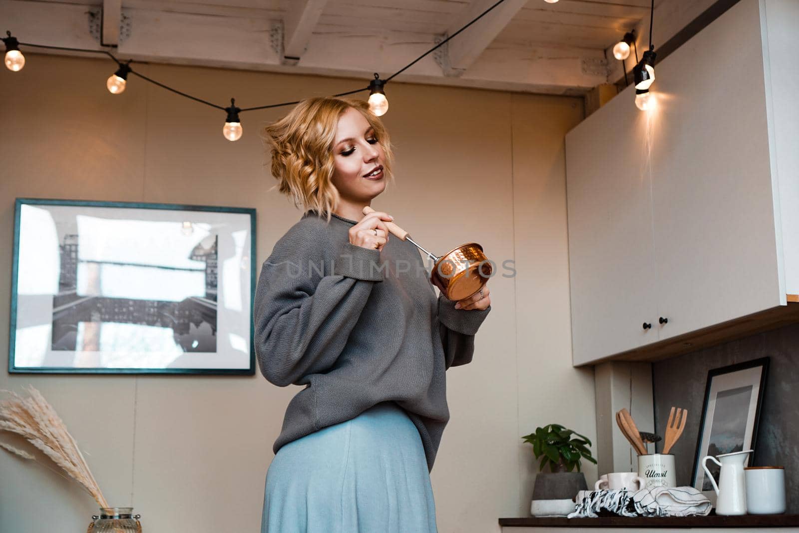 Smiling young woman standing at the kitchen, holding ladle and whisk by natali_brill