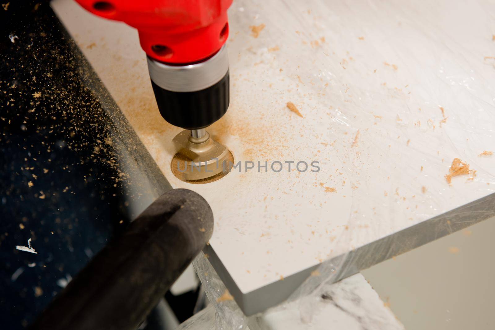 Drilling a hole for a hinge on a furniture door. Selective focus. Close up.