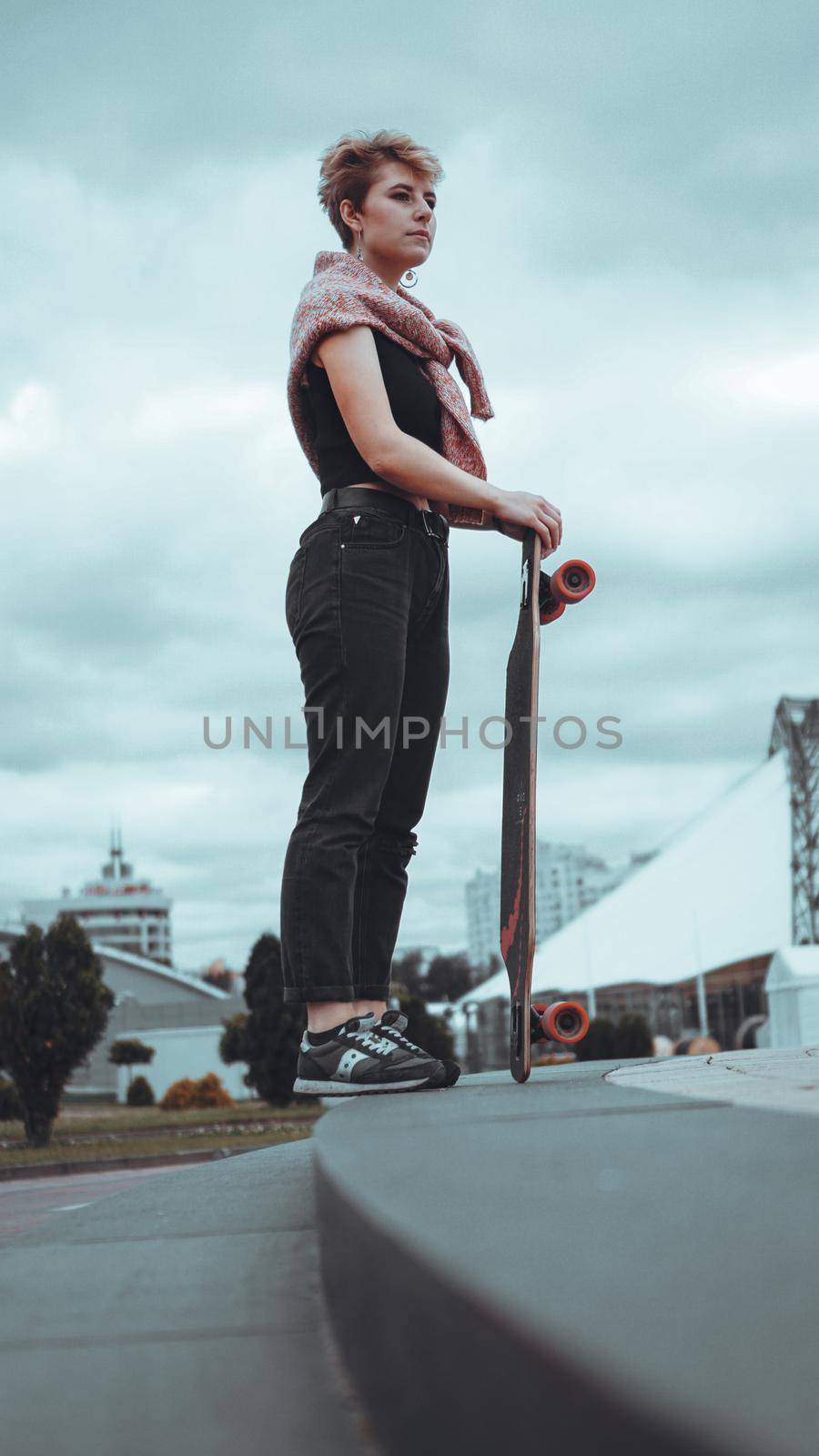 Portrait of young female skateboarder holding her skateboard by natali_brill