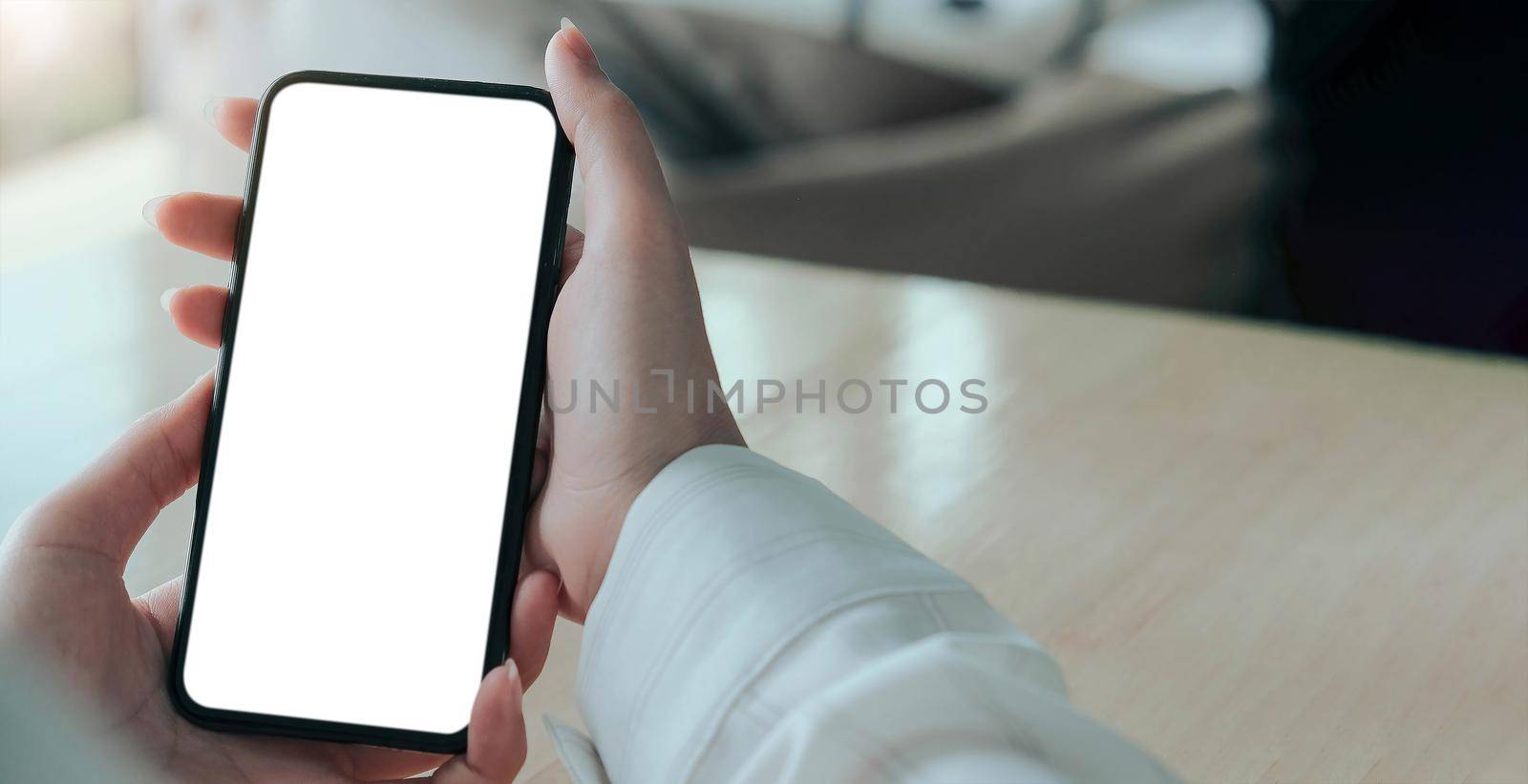 Mockup image blank white screen cell phone.women hand holding texting using mobile on desk at home office. by wichayada