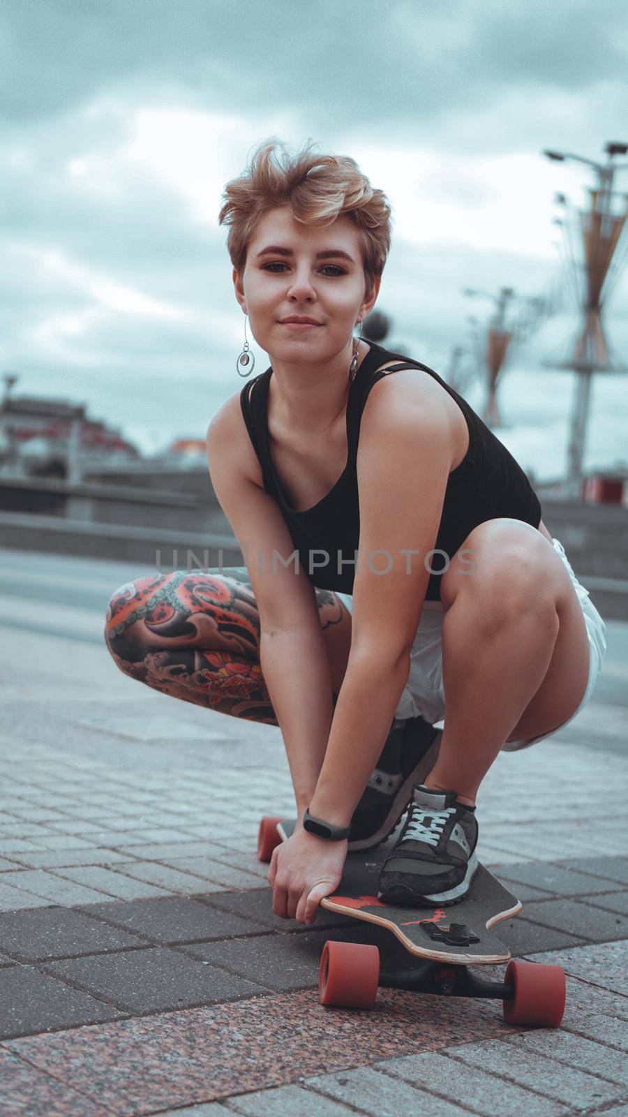 Beautiful young girl with tattoos sits on longboard by natali_brill