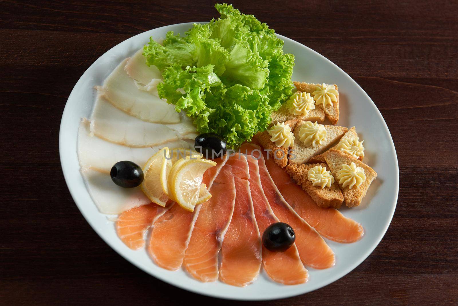 Enjoying his drink. Top view closeup of smoked sliced fish served with lemon slices and bread with butter