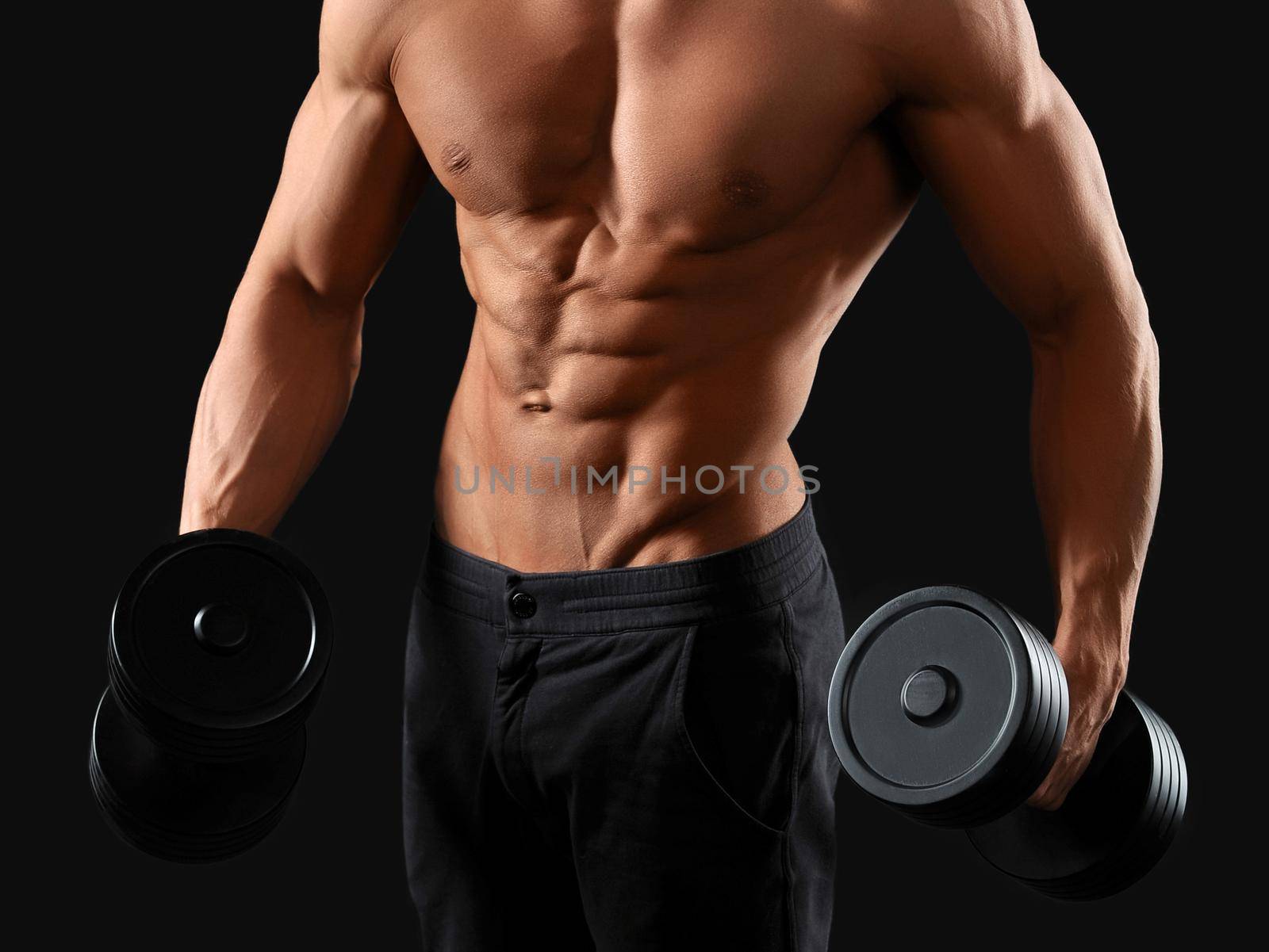Sport is a lifestyle. Cropped studio shot of a ripped man working out with dumbbells against black background