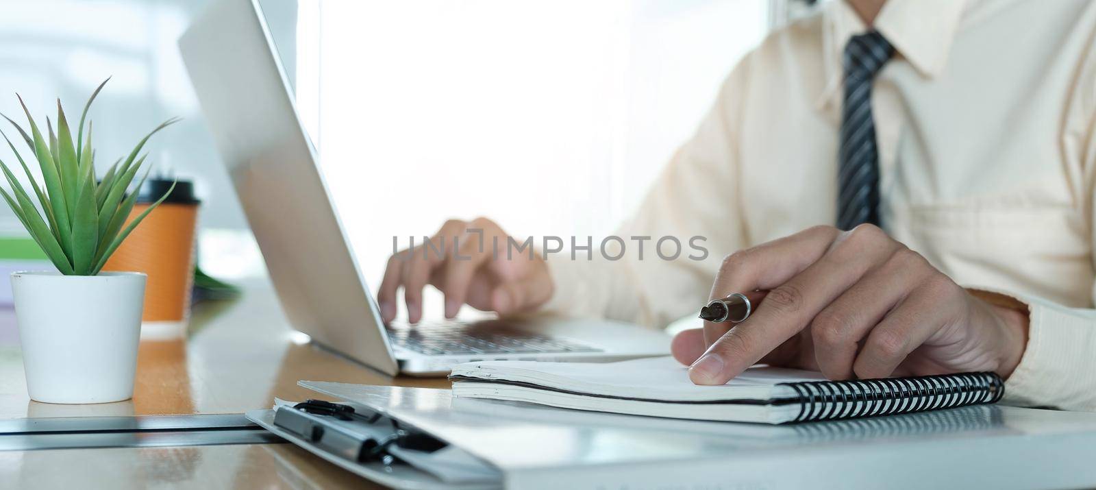Close up Businessman using laptop for do math finance on wooden desk in office and business working background, tax, accounting, statistics and analytic research concept.