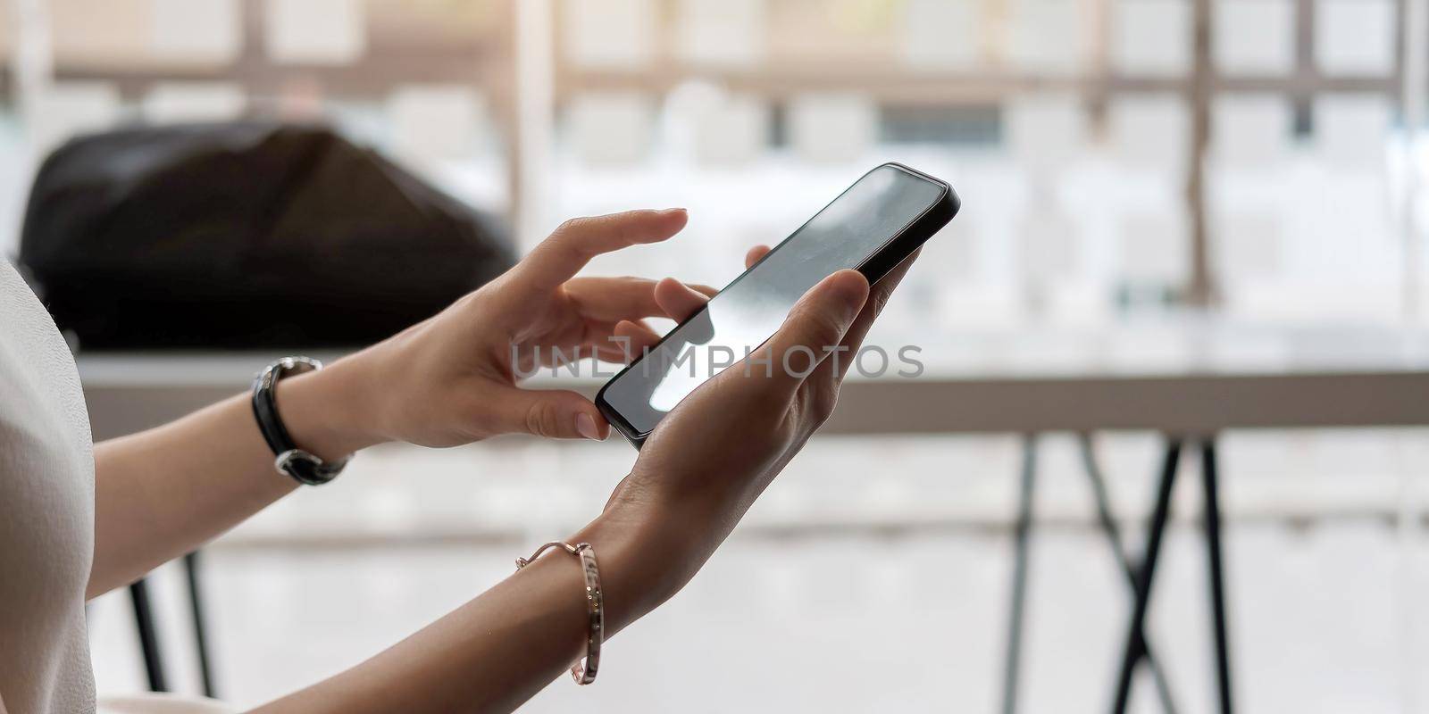 Mockup image blank white screen cell phone.women hand holding texting using mobile on desk at home office. by wichayada