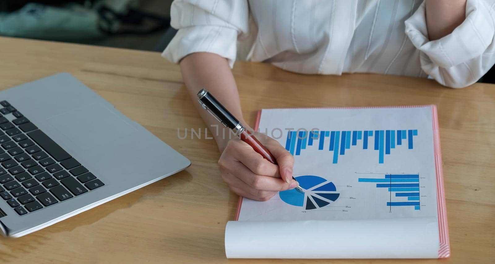 Close up of businessman or accountant hand holding pen working on calculator to calculate business data, accountancy document and laptop computer at office, business concept. by wichayada