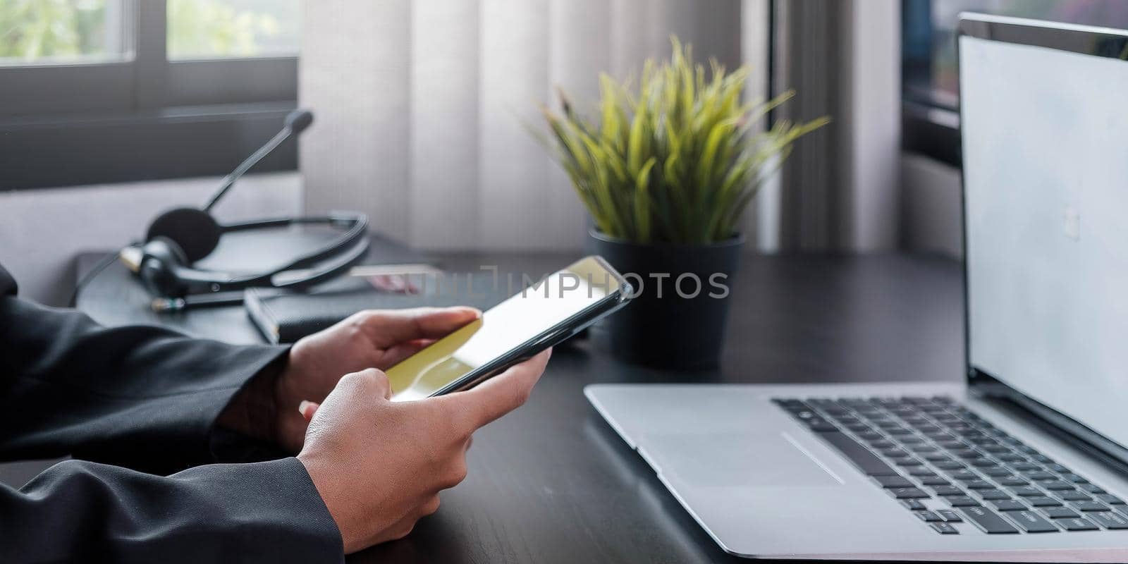 Shot of business woman holding smartphone getting message during making transaction on laptop computer.