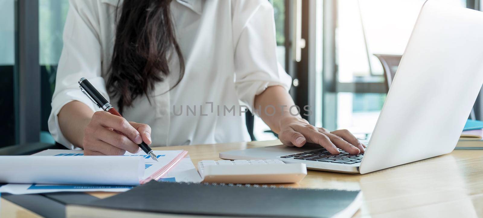 Business woman working in finance and accounting Analyze financial budget at home , Work from home concept by wichayada