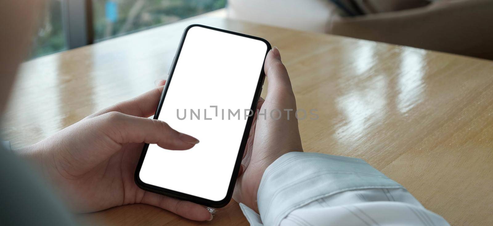 Mockup image blank white screen cell phone.women hand holding texting using mobile on desk at home office.