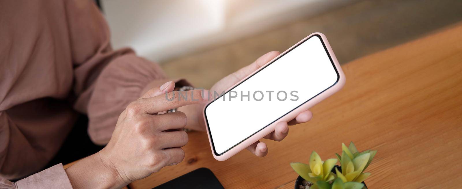 woman sitting and holding blank screen mock up mobile phone.