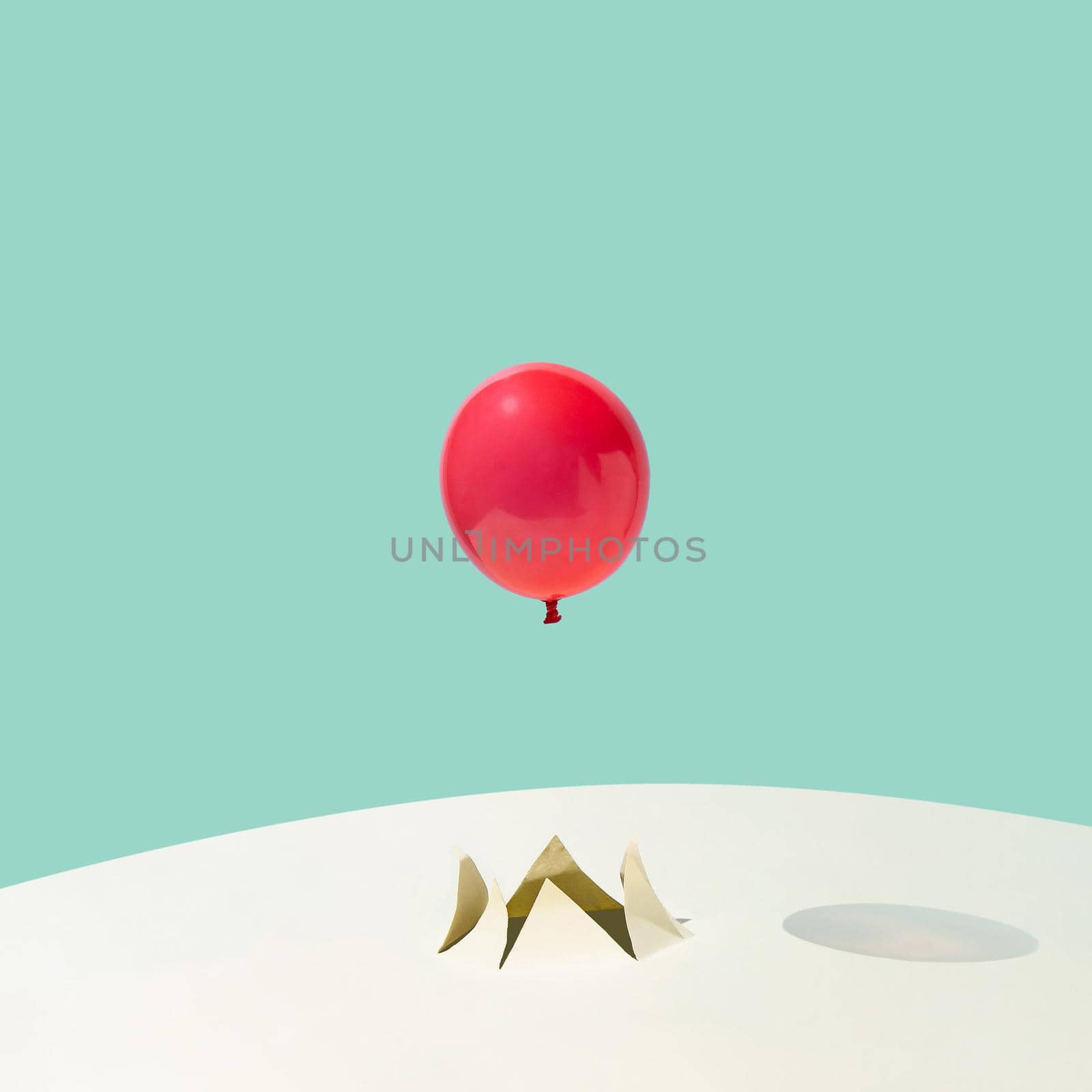 Red summer party balloon flying out of a crack on yellow and blue background. Minimal abstract concept. Square layout with copy space.