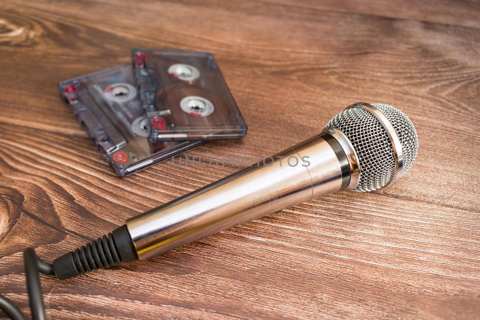 A silver-colored musical analog microphone rests next to old magnetic audio cassettes